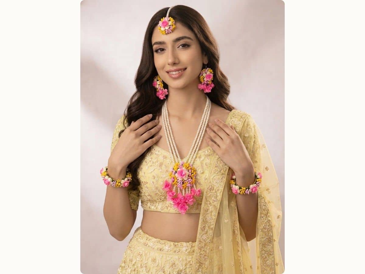Pink roses among yellow, white and lilac buds on two bracelets, earrings, maang tikka and a long layered necklace with a floral pendant